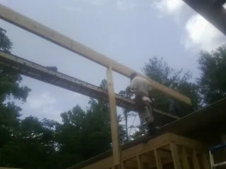 Carpenter setting a ridge beam over a new addition frame — Ice Dam Removal by Roofing Brothers in Broadbent