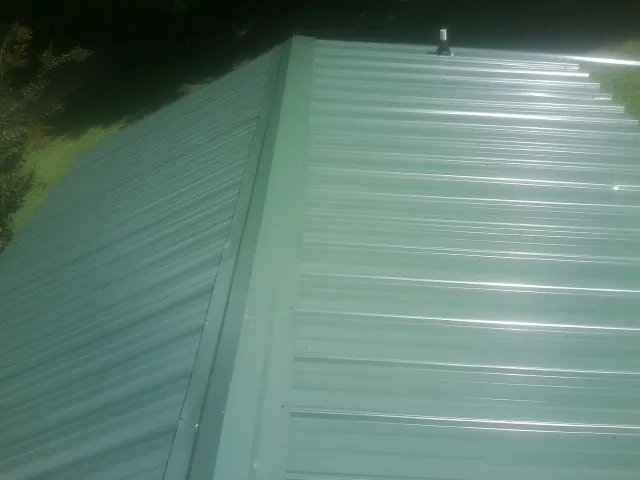 New green metal panels meeting at the ridge of a roof — Flat Roof Repair work by our crew in Broadbent