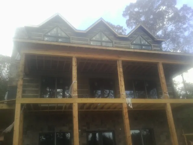 Dormers and porch framing on a large log home under construction — Roof Coating work by our crew in Broadbent
