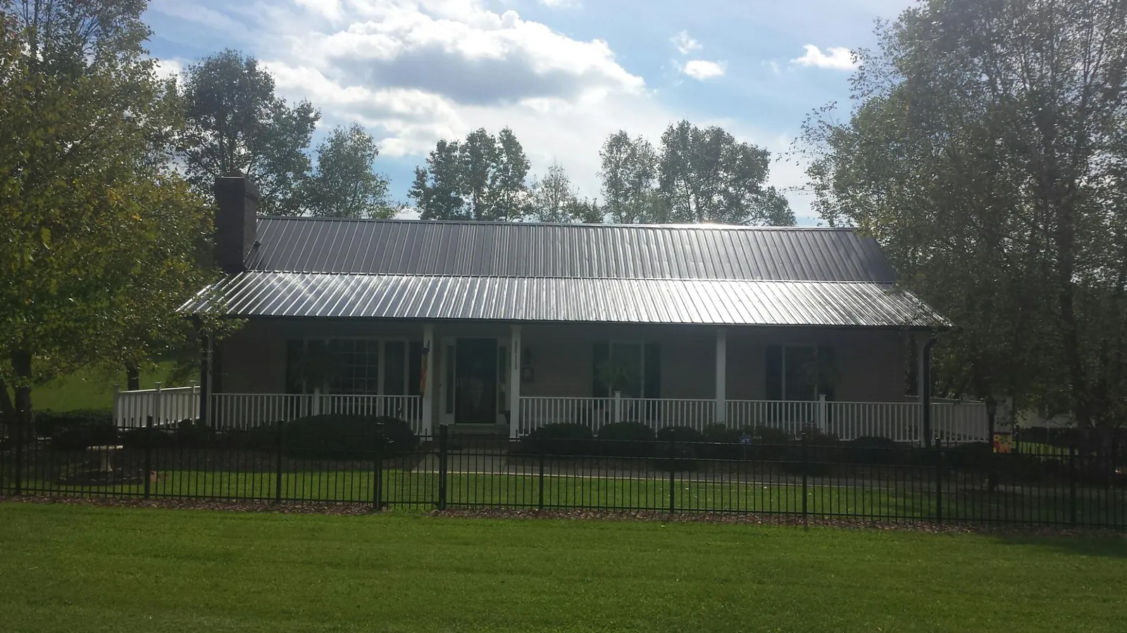 Gray metal roof on a brick ranch with a full width front porch — Gutter Guard Installation work by our crew in Broadbent