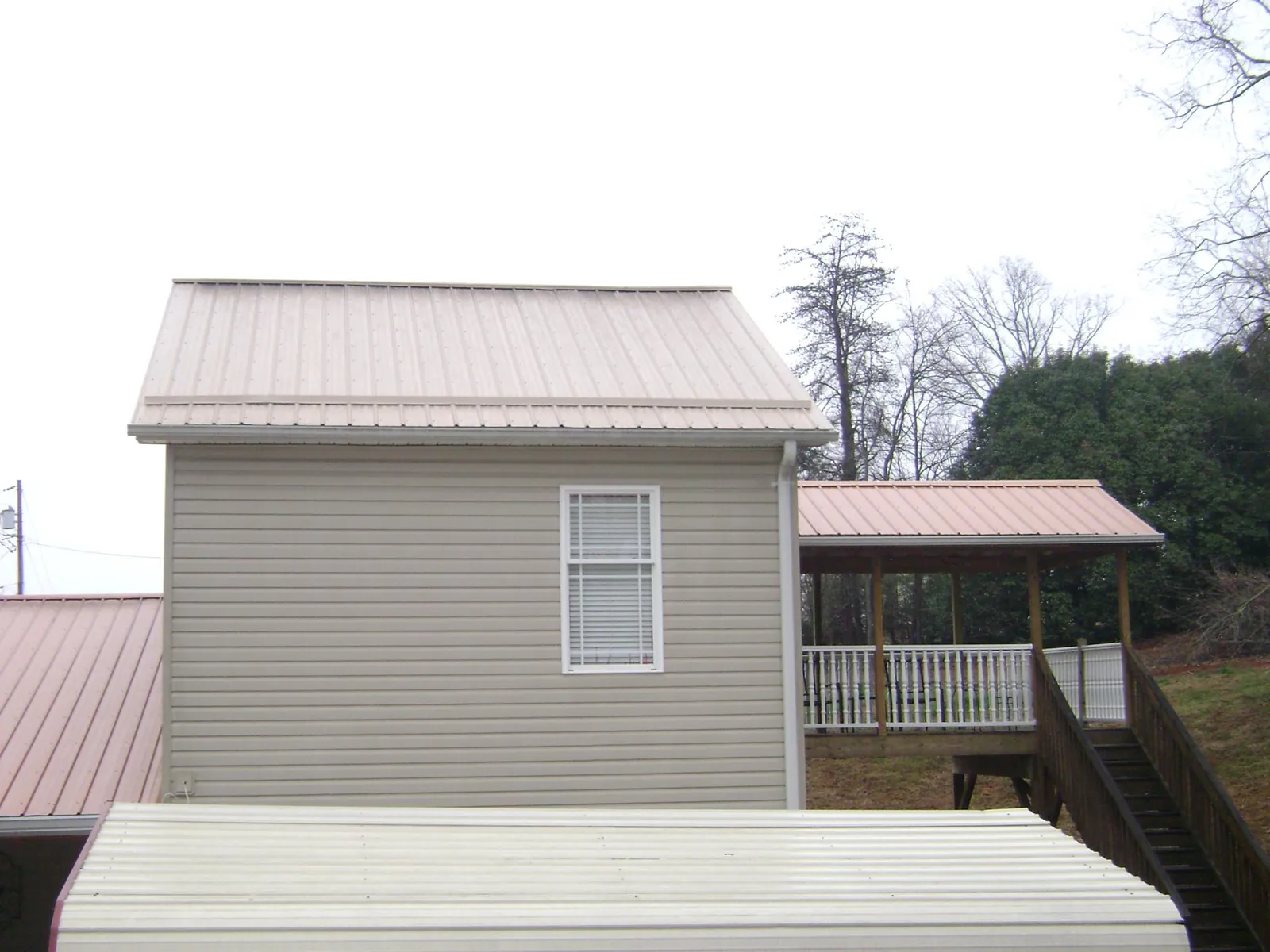 Tan metal roofs on a two story addition and attached porch, from a Roof Replacement job in Broadbent