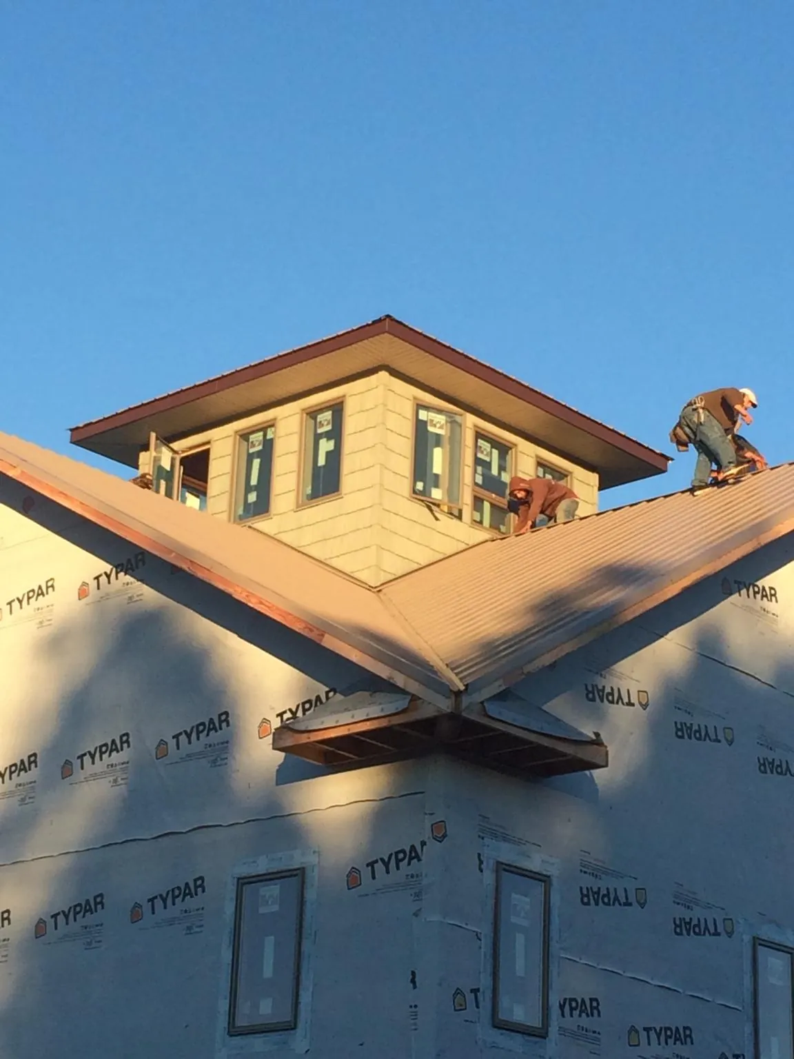 Roofers working around a rooftop cupola on a new metal roof at sunset — Roof Waterproofing in Broadbent by Roofing Brothers